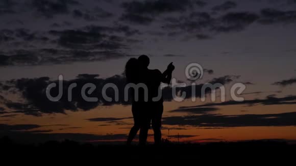 浪漫情侣舞蹈的黑暗剪影在猩红的夕阳下旋转视频的预览图