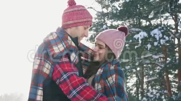 女孩和男人在阳光明媚的冬日森林里格子红色格子呢视频的预览图