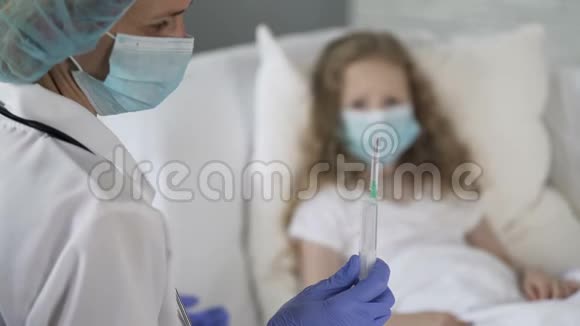 带着口罩看着手里拿着注射器的护士一个不高兴的害怕的孩子视频的预览图