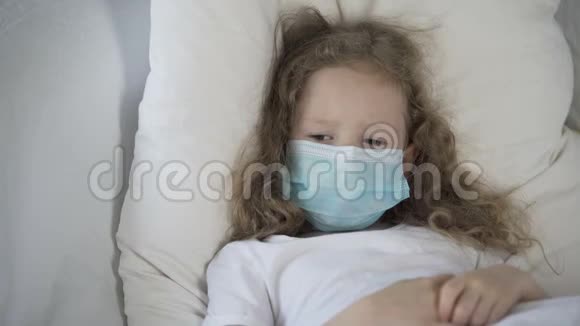 伤心的孩子戴着医用口罩躺在床上患有罕见病流行病视频的预览图