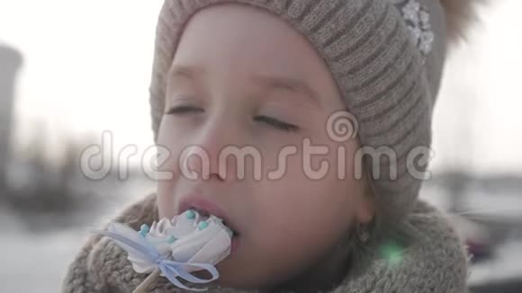 可爱的小女孩在美丽的棒棒糖在美丽的冬日生活方式户外视频的预览图