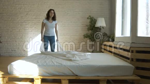 年轻漂亮的女人在整理床铺视频的预览图