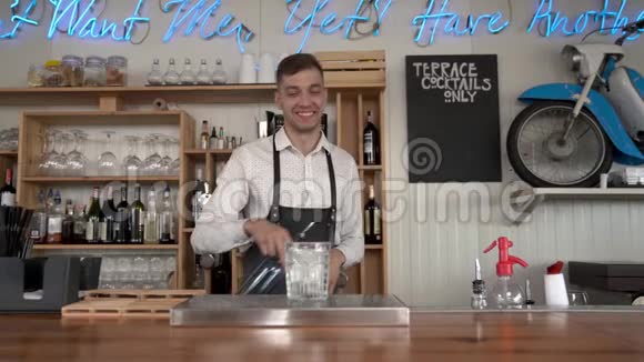 一位年轻英俊的酒保把一杯蓝色的库拉索酒倒入装有冰块的玻璃杯中视频的预览图