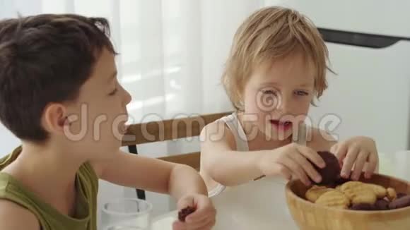 两个男孩在家厨房吃自制的带牛奶的饼干视频的预览图