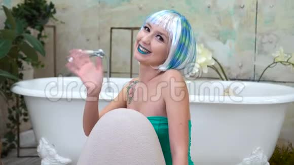 一位戴着假发微笑着的美丽女人正在浴室里挥手的肖像视频的预览图
