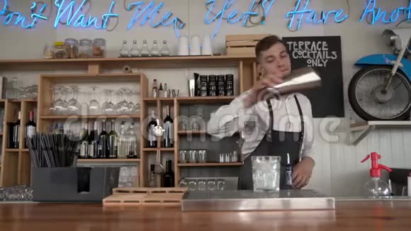 一家酒吧招待一个酒保把一杯蓝色的curacao酒倒入一个装有冰块的视频的预览图