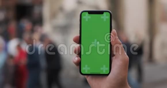 特写一个男人手拿着一部移动电话街道上有一个垂直的绿色屏幕视频的预览图