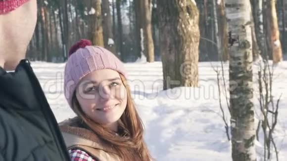 一个迷人的女孩正和一个男人在冬天的森林里散步视频的预览图