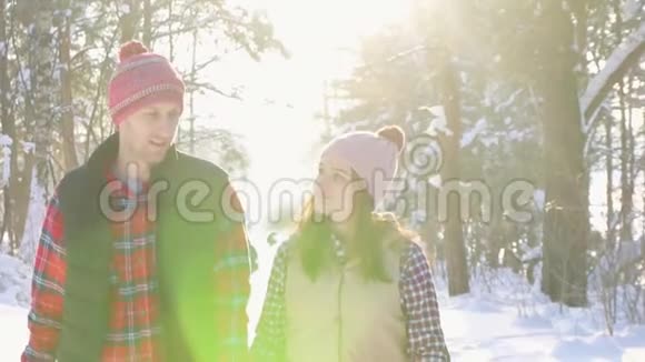 在一个阳光明媚的日子里女孩和一个年轻人牵着手微笑着沿着冬天的公园散步视频的预览图