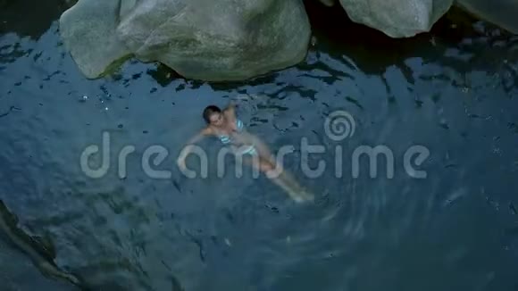 迷人的女人放松在清澈的河水空中拍摄年轻女子在河中无人驾驶的视野中游泳放松和享受视频的预览图