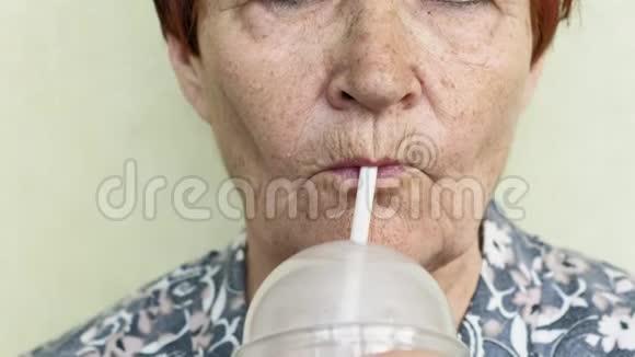 一位老妇人喝着一杯稻草特写的饮料视频的预览图