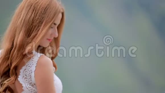 红发神秘浪漫新娘穿着别致的礼服带着一束鲜花和青山视频的预览图