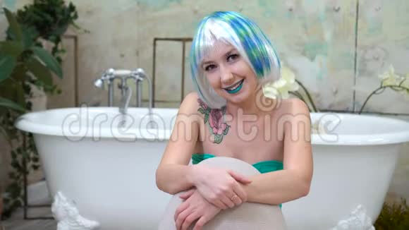 戴着假发的年轻美丽的微笑女人在镜头前沐浴的肖像视频的预览图