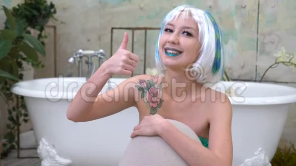 戴假发的快乐微笑女孩在浴室里竖起大拇指视频的预览图