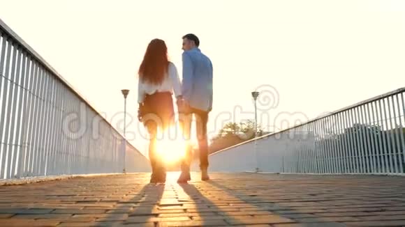 一对年轻的男女在夏天走在桥上日落的光时尚快乐的商务服装搭配视频的预览图