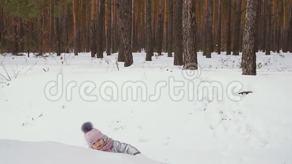 冬天森林里可爱的小女孩在山上爬行视频的预览图