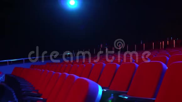 电影院大厅里空空的一排座位带红色座位的空电影院黑暗的房间里投影仪灯亮着视频的预览图