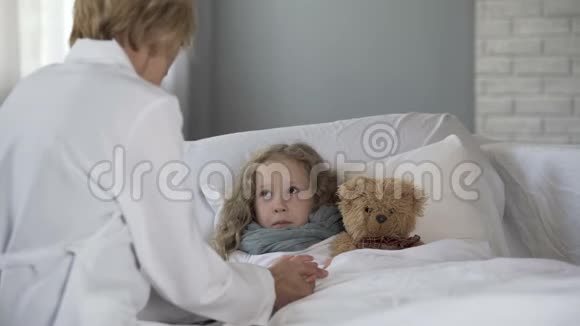 女医生手牵着生病的女孩与她交谈在家治疗视频的预览图