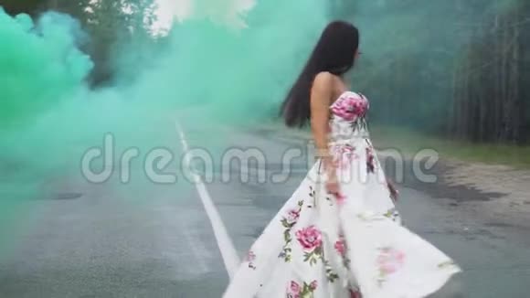 可爱的女孩穿着一件长裙子在彩色烟雾中旋转视频的预览图