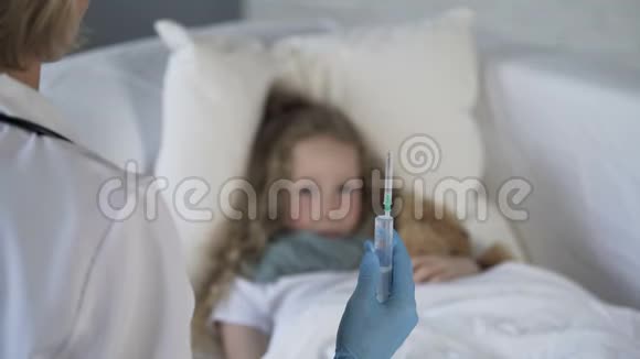 带着恐惧的脸看着医生手中的注射器的女孩视频的预览图