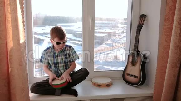 演奏乐器男孩坐在窗台上打鼓视频的预览图