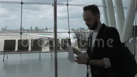年轻的商人拿着机票和护照站在机场大楼里视频的预览图