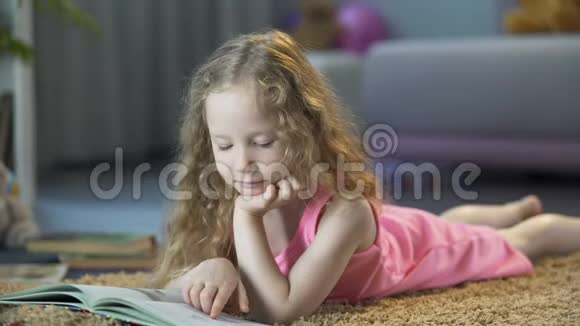 好奇的小女孩躺在地上读着有趣的儿童故事书视频的预览图