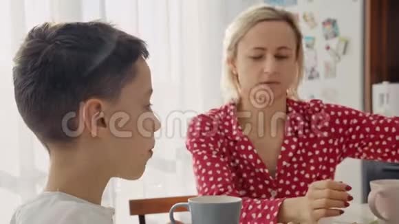 一个可爱可爱的白种人男孩正在他金发的年轻母亲旁边吃饼干视频的预览图
