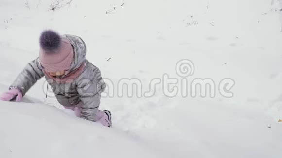 可爱的女孩沿着雪山爬行视频的预览图