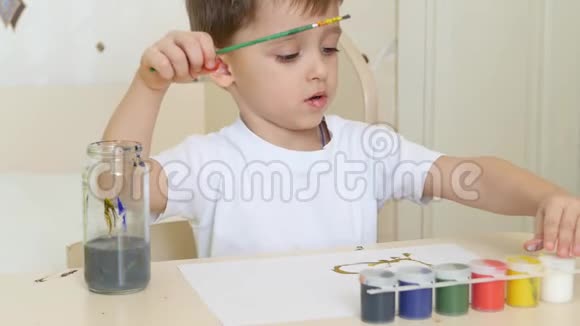 小男孩用水粉在一张白纸上画画特写镜头视频的预览图