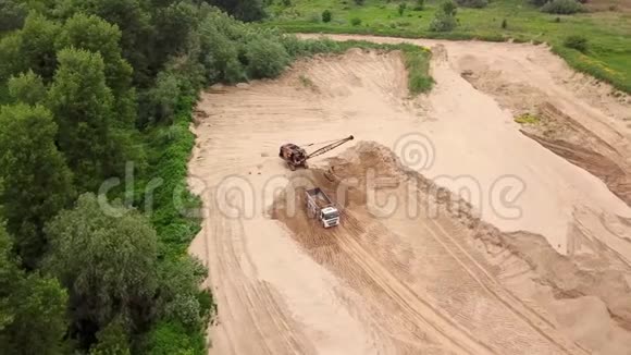 从上往下看挖掘机把沙子倒进卡车靠近树木在施工现场视频的预览图