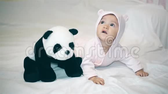 一个穿着熊服和熊猫在床上玩耍的小女孩视频的预览图