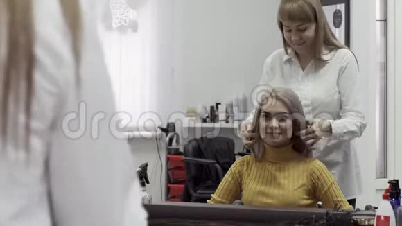 穿白色衬衫的年轻女性美容师给女孩带来发型视频的预览图