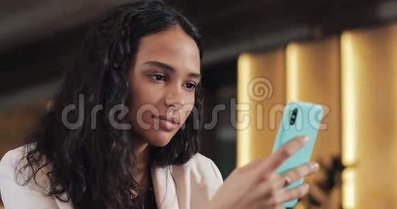 年轻商务女性在舒适的咖啡店使用手机她浏览网上留言和回复短信视频的预览图