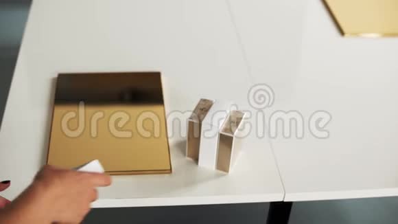 穿黑色t恤的女人把小盒子香水放在灯光室的白色桌子上视频的预览图