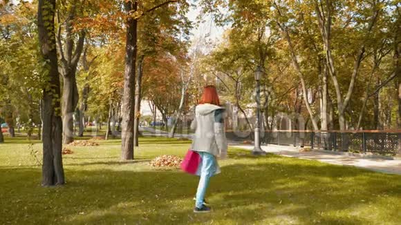 一个长着狐假虎威的女孩穿着五颜六色的纸袋穿过公园视频的预览图