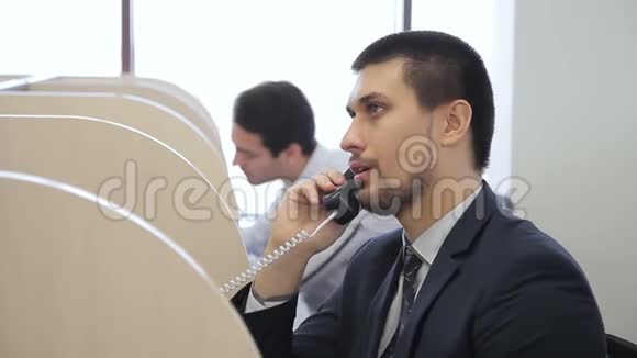 男性接线员坐在现代办公室时打电话视频的预览图