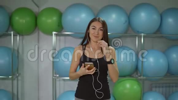 带着耳机在体操球背景下健身的年轻女子视频的预览图