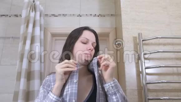 刚在浴室里宿醉醒来的睡眼的女人把衬衫系紧使自己井井有条视频的预览图