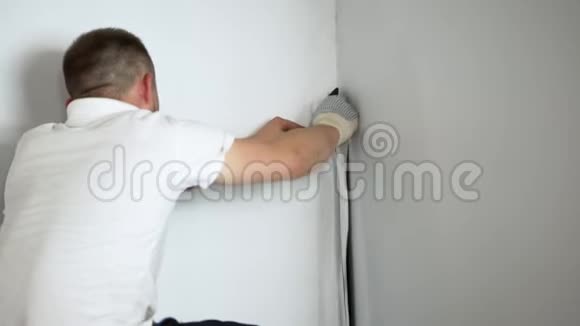 穿白色t恤的男人坐在墙旁边手里拿着白色的条纹视频的预览图