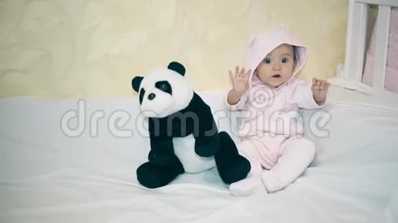 一个小孩躺在熊猫旁边的白色毯子上视频的预览图