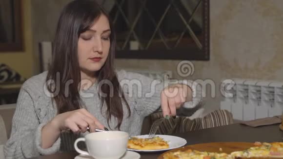 披萨饼一个黑发女人在咖啡馆吃披萨视频的预览图