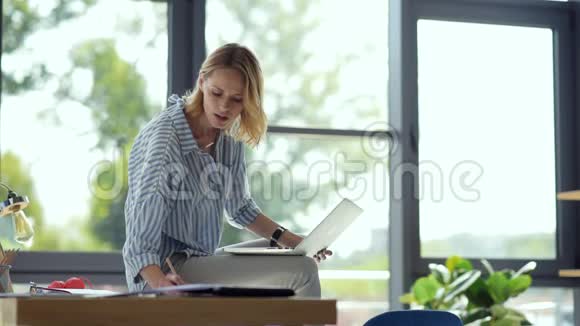 快乐的女学生坐在桌上上网学习视频的预览图