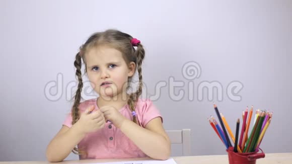 可爱的女孩说话手里拿着一支蓝色的铅笔视频的预览图