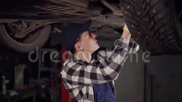 英俊的机械师在他的车间里从底部爬行一辆车视频的预览图