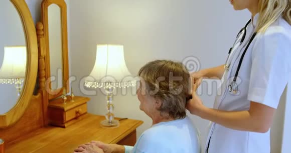 医生在梳妆台4k上梳理高级女性的头发视频的预览图