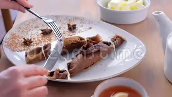 女人正在吃俄式巧克力薄饼在盘子里用豆腐馅双手特写提供茶视频的预览图
