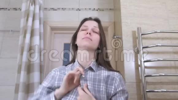 刚在浴室里宿醉醒来的睡眼的女人把衬衫系紧使自己井井有条视频的预览图