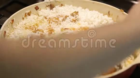 家庭主妇在厨房的煤气炉上给米饭和烤肉加水煮饭视频的预览图
