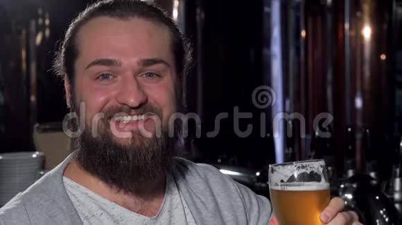 大胡子的快乐男人微笑着举起他的啤酒杯对着镜头视频的预览图